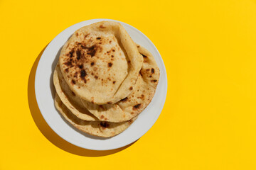 Egyptian bread Aish Baladi on. A lot of fresh bread lies on the yellow table