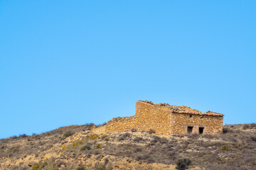 Ruined old spanish country house on scrub hill and blue sky