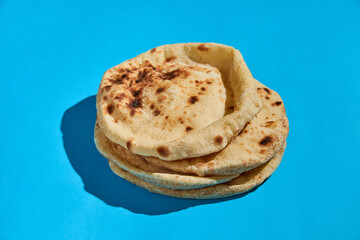 Egyptian bread Aish Baladi. A lot of fresh bread lies on the blue table