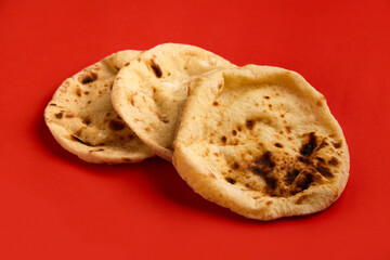 Egyptian bread Aish Baladi. A lot of fresh bread lies on the red table