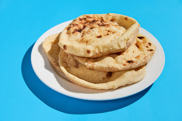 Egyptian bread Aish Baladi. A lot of fresh bread lies on the blue table