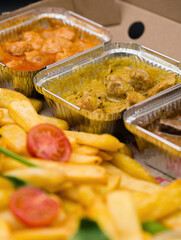 meat, chicken and pork dishes with sauces and French fries, served in an aluminum tray for home delivery