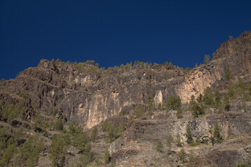 Fototapeta na wymiar Gran Canaria, landscape of the southern part of the island along Barranco de Arguineguín steep and deep ravine with vertical rock walls, circular hiking route starting at a hamlet Barranquillo Andres 