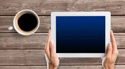 tablet computer with blank screen and cup of tea or coffee