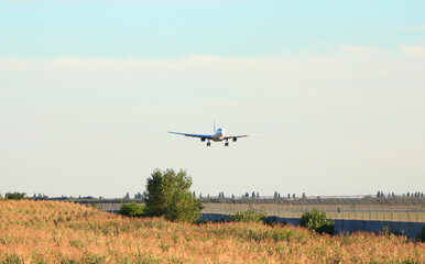 Passenger plane over the forest in the blue sky, the sun is shining. Transport, travel. High...