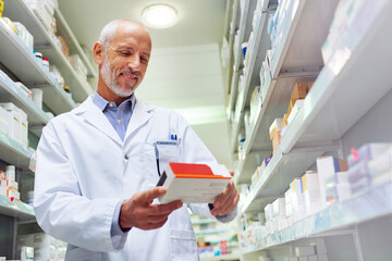 Hes meticulous when it comes to medicinal management. Shot of a mature pharmacist doing inventory...