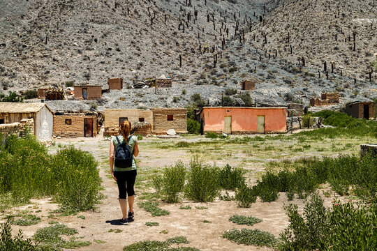 Tourist woman walks towards adobe houses in San Bernardo de las Zorras in Salta, Argentina