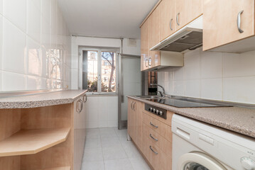 Furnished kitchen with similar pink granite countertop with white appliances, aluminum window and door to the terrace and black ceramic hob in rental apartment
