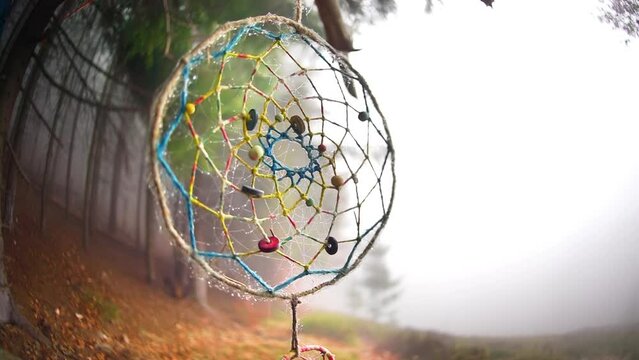 Pagan solar symbol amulet hanging on a tree branch in a misty Shipot forest. Mystical hippie lifestyle concept, neo-pagan culture and boho style talisman in atmospheric foggy Carpathians, Ukraine.