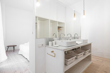 Individual sinks on lacquered wood cabinet with marble top and large mirror in dressing room in vacation rental apartment