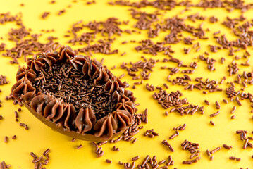 Easter egg filled with granulated chocolate, Easter concept on yellow background.