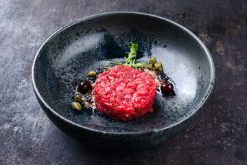 Modern style gourmet tartar raw from beef filet with capers and amarena cherry served with truffle...