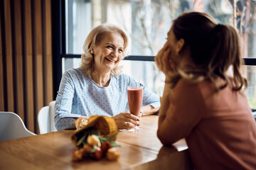 Happy senior woman talks to her daughter on Mother's day in cafe.
