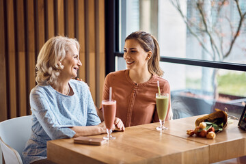Happy woman and her senior mother talk while enjoying on Mother's day in cafe.