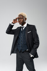 elegant african american model in formal wear posing with hand in pocket isolated on grey