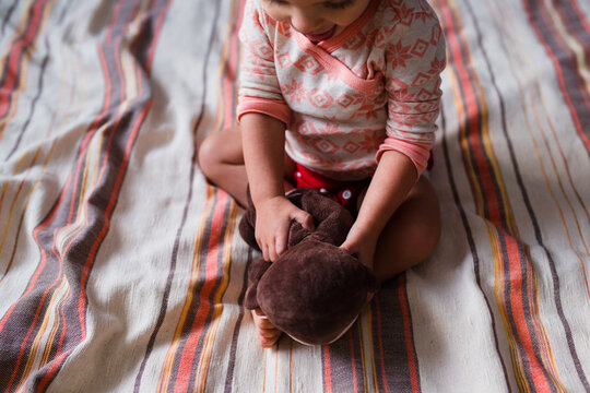 Girl Plays With Stuffed Monkey On Bed