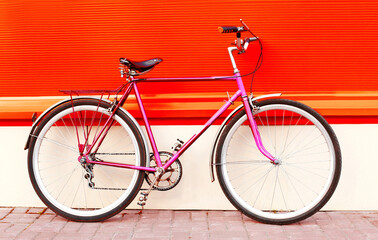 Colorful image retro pink bicycle standing in the city on vivid background