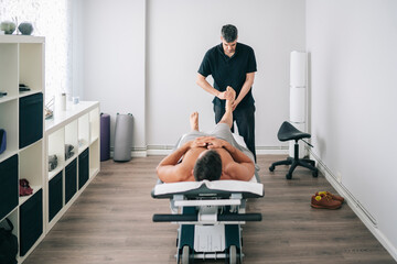Chiropractor massaging legs of patient in modern clinic