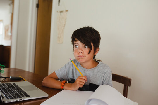 Boy attending homeschooling class through laptop at table in living room