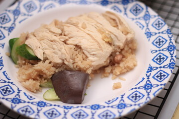 Chicken rice and boiled chicken served in a white plate with blue stripes.