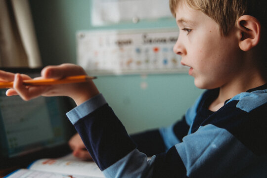 A little boy listens to a zoom call.