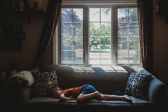 A little boy lies on a couch.