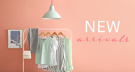 Rack with stylish clothes and text NEW ARRIVALS on pink background
