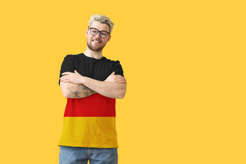 Young man wearing t-shirt in colors of German flag on yellow background