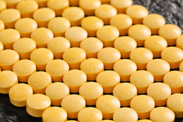 Yellow pills on dark background, closeup