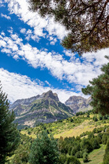 a mountain range framed with vegetation at the edges, on a summer day with a sky with cottony clouds, Pena Telera, Valle de Tena, Biescas, Huesca, Spain