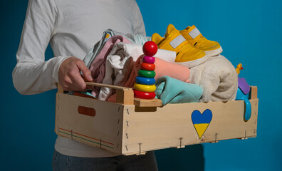 Close up of volunteer holding box with Humanitarian aid with children's things and toys for...