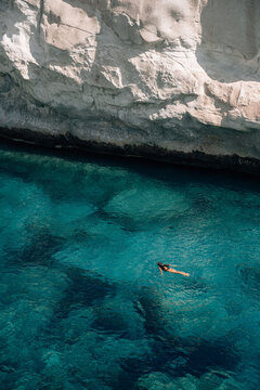 Distant woman swimming in clear turquoise sea