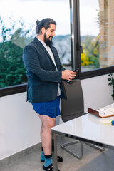 young businessman looking at mobile phone standing without trousers