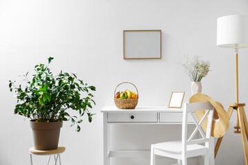 White workplace with fruit basket near light wall