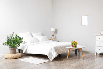 Interior of light bedroom with table and fruit basket