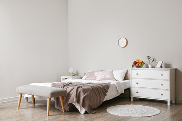 Interior of light bedroom with chest of drawers and fruit basket