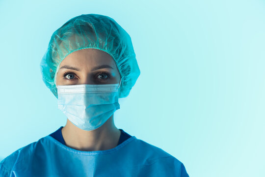 Female Surgeon Wearing protective face mask and protective suit portrait on blue background . High quality photo