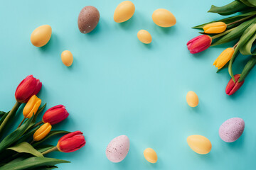 Happy Easter concept. Festive blue background with decorated eggs and colorful tulips. Top view, flat lay, copy space