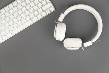 Background music or podcast with headphones and a computer keyboard on a gray table, flat. Top view, flat layout