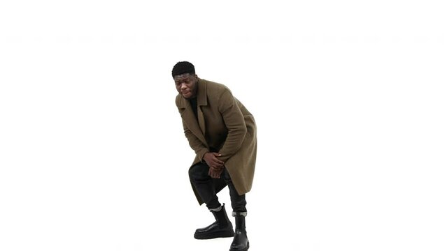 Afroamerican man bending and posing brown coat white background - full shot. High quality 4k footage