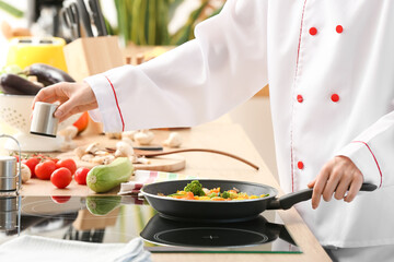 Female chef frying vegetables in kitchen, closeup