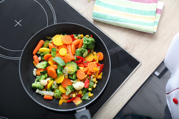 Frying pan with healthy vegetables on stove - obrazy, fototapety, plakaty