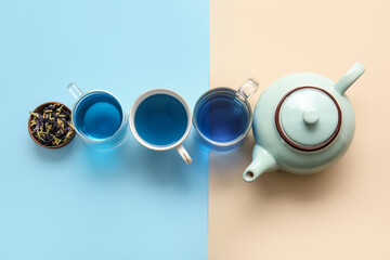 Cups of blue tea and dried butterfly pea flowers on color background