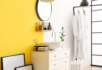 Interior of stylish bathroom with drawers, sink and mirror