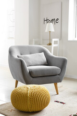 Grey armchair and yellow pouf in light living room