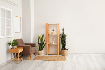 Interior of light living room with armchair, shelving unit and houseplants