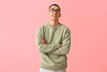 Handsome young Asian man in knitted sweater on pink background