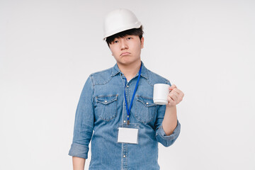 Tired sad exhausted overworked asian korean young male architect drinking coffee for wake up energy after hard-working day isolated in white background. Nightshift concept