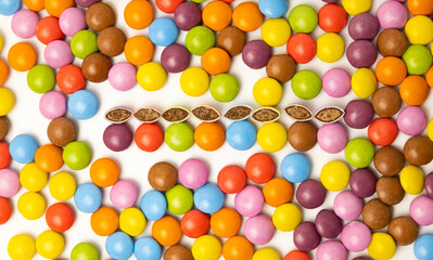 Obraz premium View from above. Chocolate candies of different colors laid out on a white background. The candies are cut in half. Harmful baby food