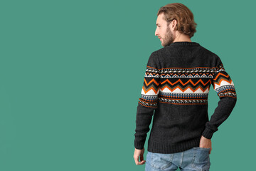 Handsome young man in knitted sweater on color background